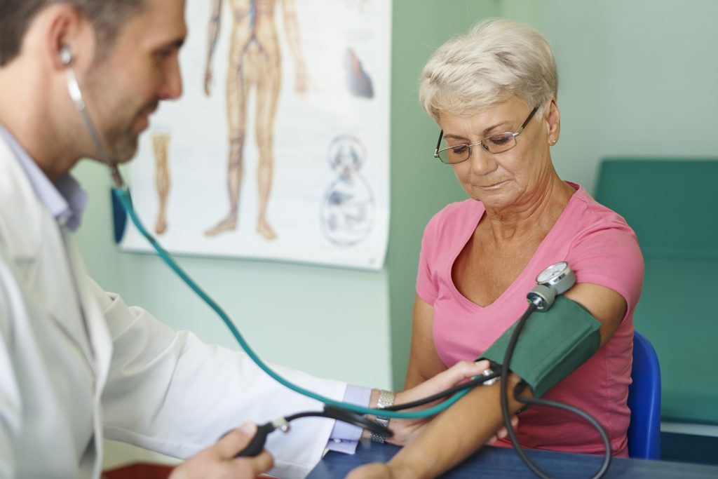 Doctor checking older patients blood pressure.