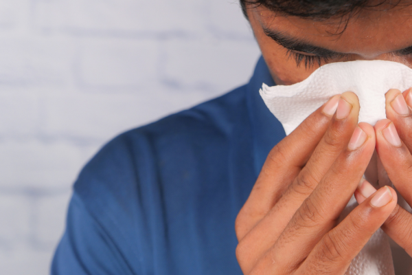 man blowing nose because of allergies