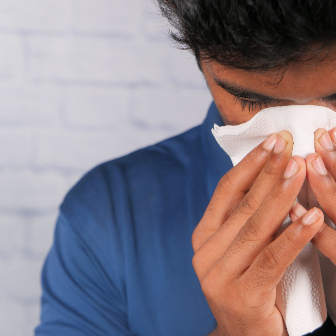 man blowing nose because of allergies