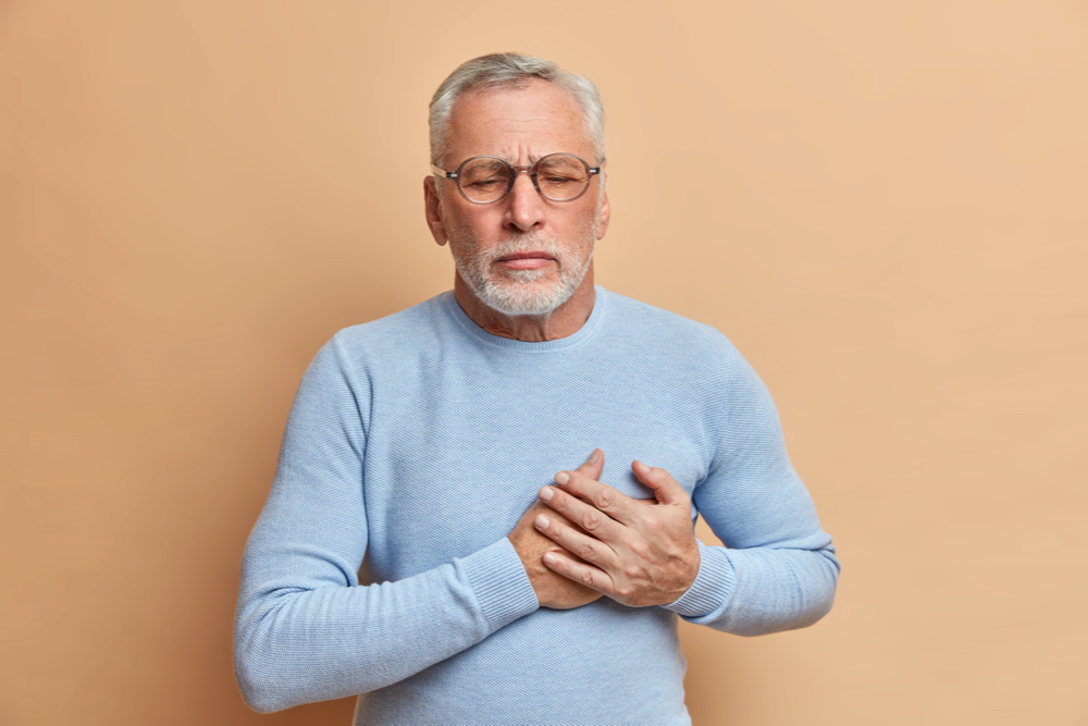 Older man holding chest thinking he is having a heart attack