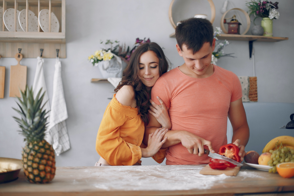 young couple cutting fruits and vegetables in kitchen