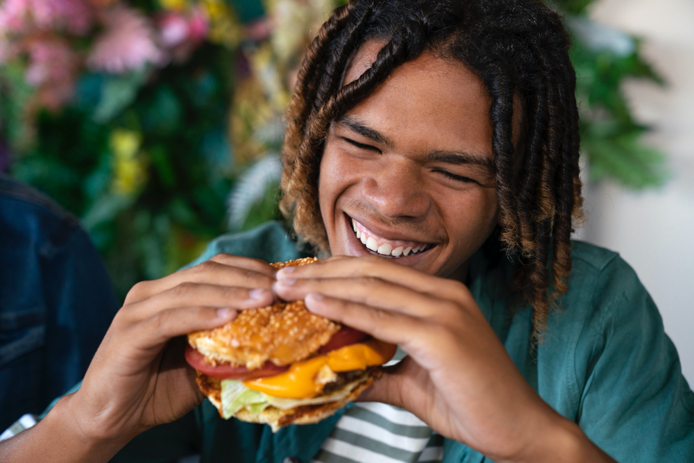 photo front view man eating burger in a funny way